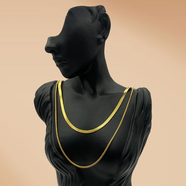 Black mannequin wearing a gold necklace against a beige background