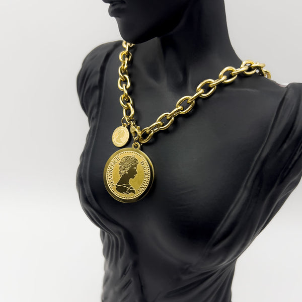 Gold chain necklace with a medallion on a black mannequin against a white background