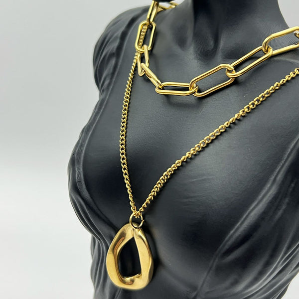 Gold chain necklace with a pendant on a mannequin bust against a gray background
