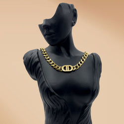 Mannequin wearing a gold chain necklace with a logo on a beige background
