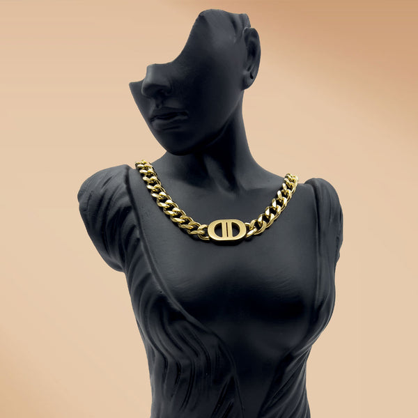 Mannequin wearing a gold chain necklace with a logo on a beige background