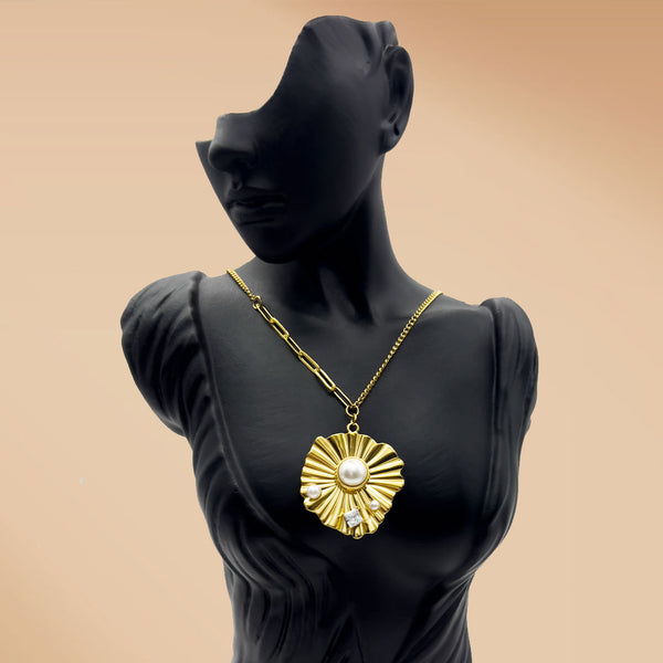 Gold necklace with a sunflower pendant on a black mannequin against a beige background