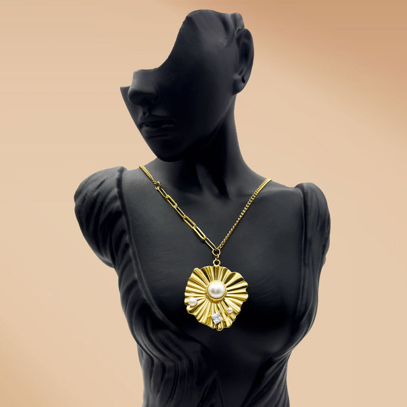Gold necklace with a sunflower pendant on a black mannequin against a beige background