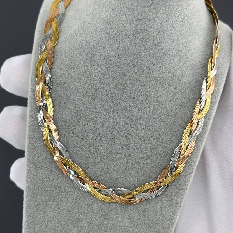 Tri-color chain necklace on a gray jewelry display