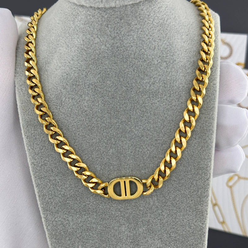 Gold chain necklace on a gray stand with a blurred background